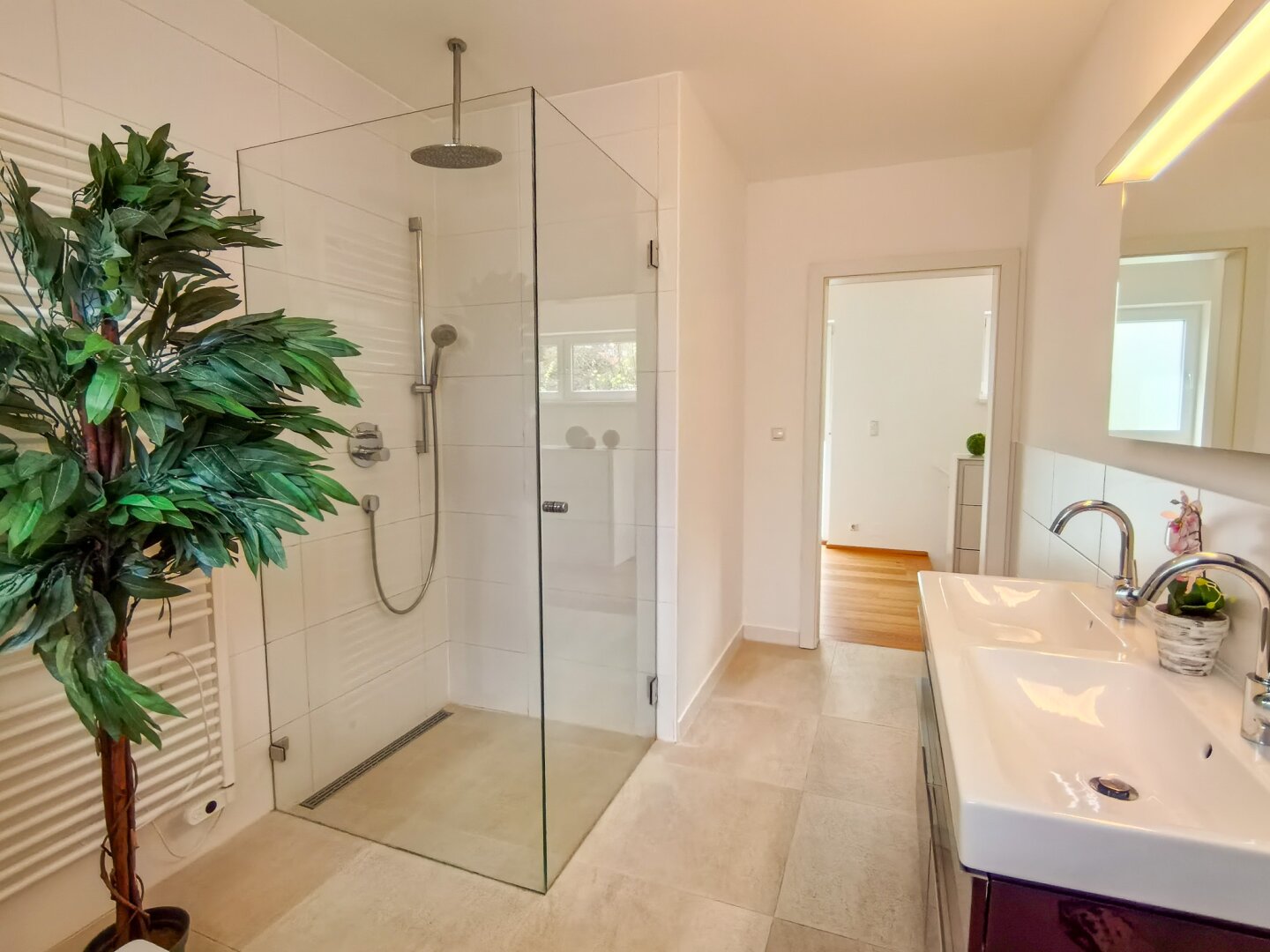 Bad mit Handtuchtrockner, Fußbodenheizung und moderner Dusche.